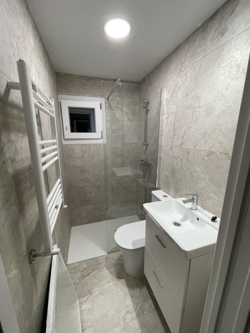 Bathroom in beige marble-look porcelain with walk-in shower and towel radiator