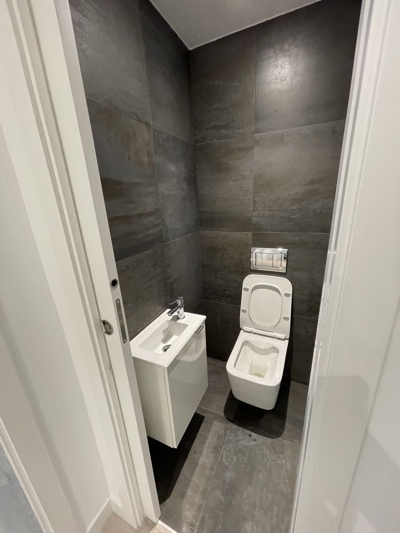 Powder room in large-format dark porcelain with wall-hung toilet and compact vanity