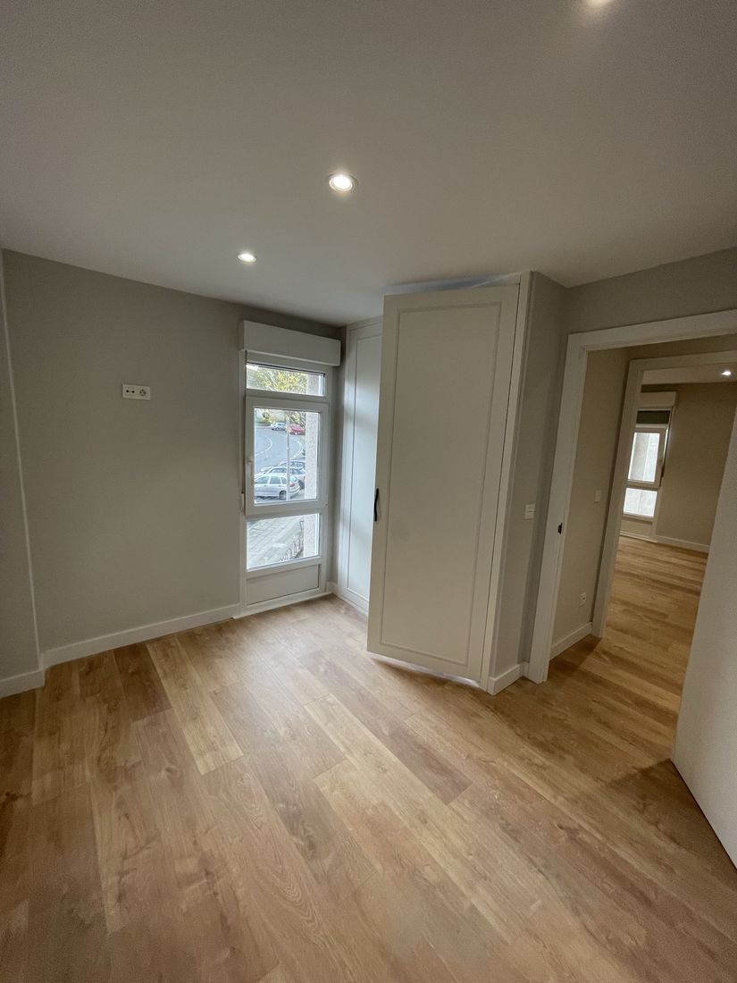 Bedroom with built-in paneled wardrobe, oak-look floor and recessed lighting