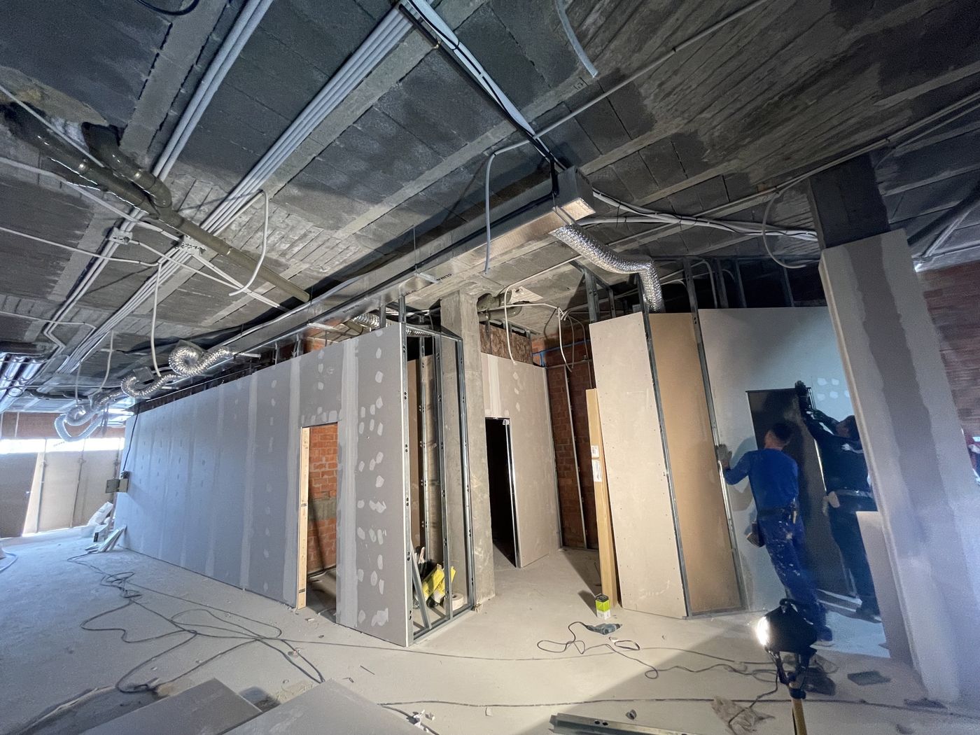 Crew installing steel stud framing and drywall partitions on a commercial fit-out
