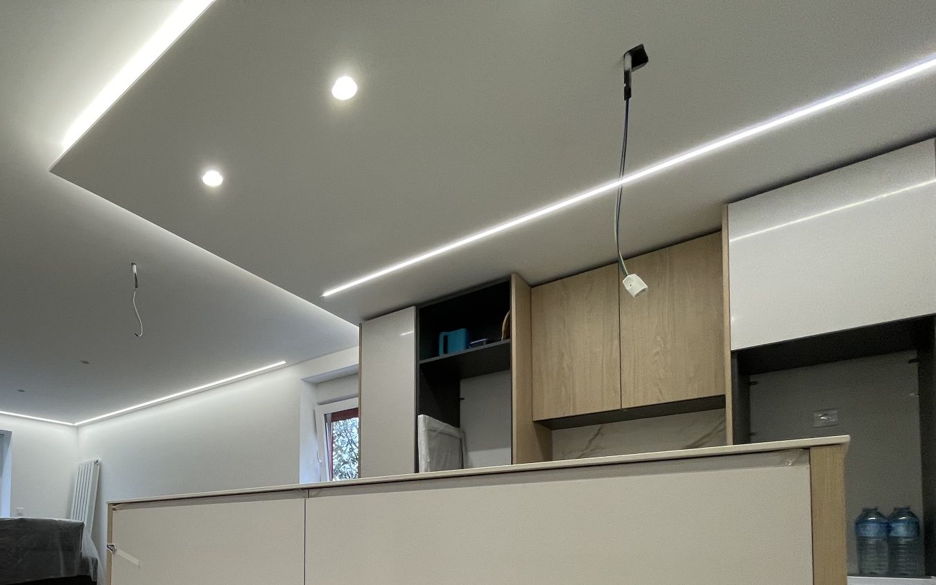 Kitchen island with handleless white drawers under a dropped ceiling with linear LED lighting
