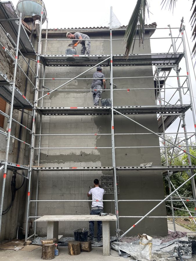 Three-man crew rendering a facade from a scaffold