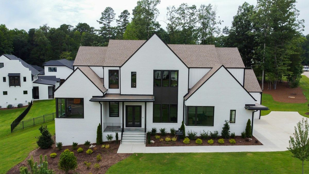 White modern farmhouse with dark roof and landscaped yard