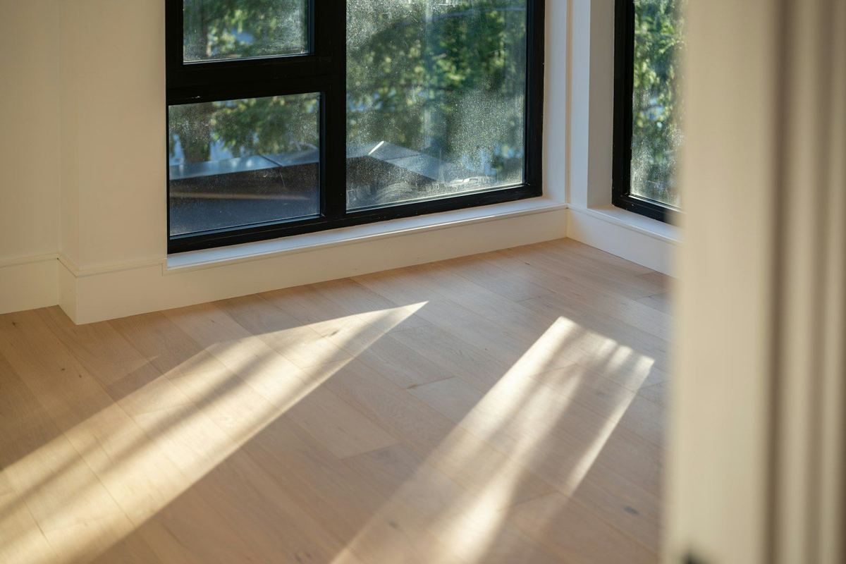 Light oak hardwood floor with sunlight from black-framed windows
